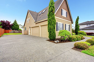 Clapboard siding house with two car garage and driveway. Viw of green beautitul landscape
